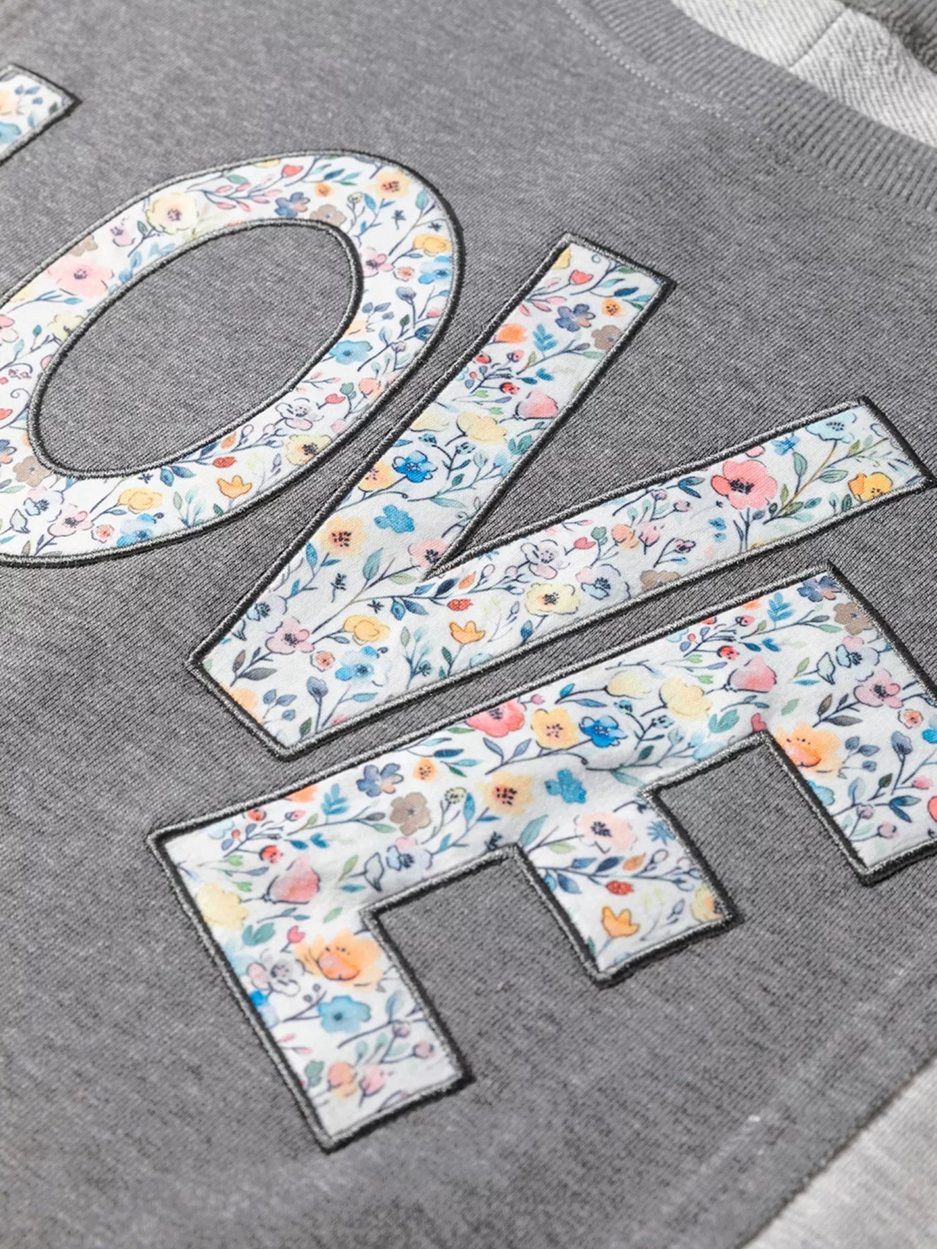 LOVE Graphic Exposed Seam Patchwork Uneven Hem Chic Sweatshirt designed for comfort and style at Lookzlike