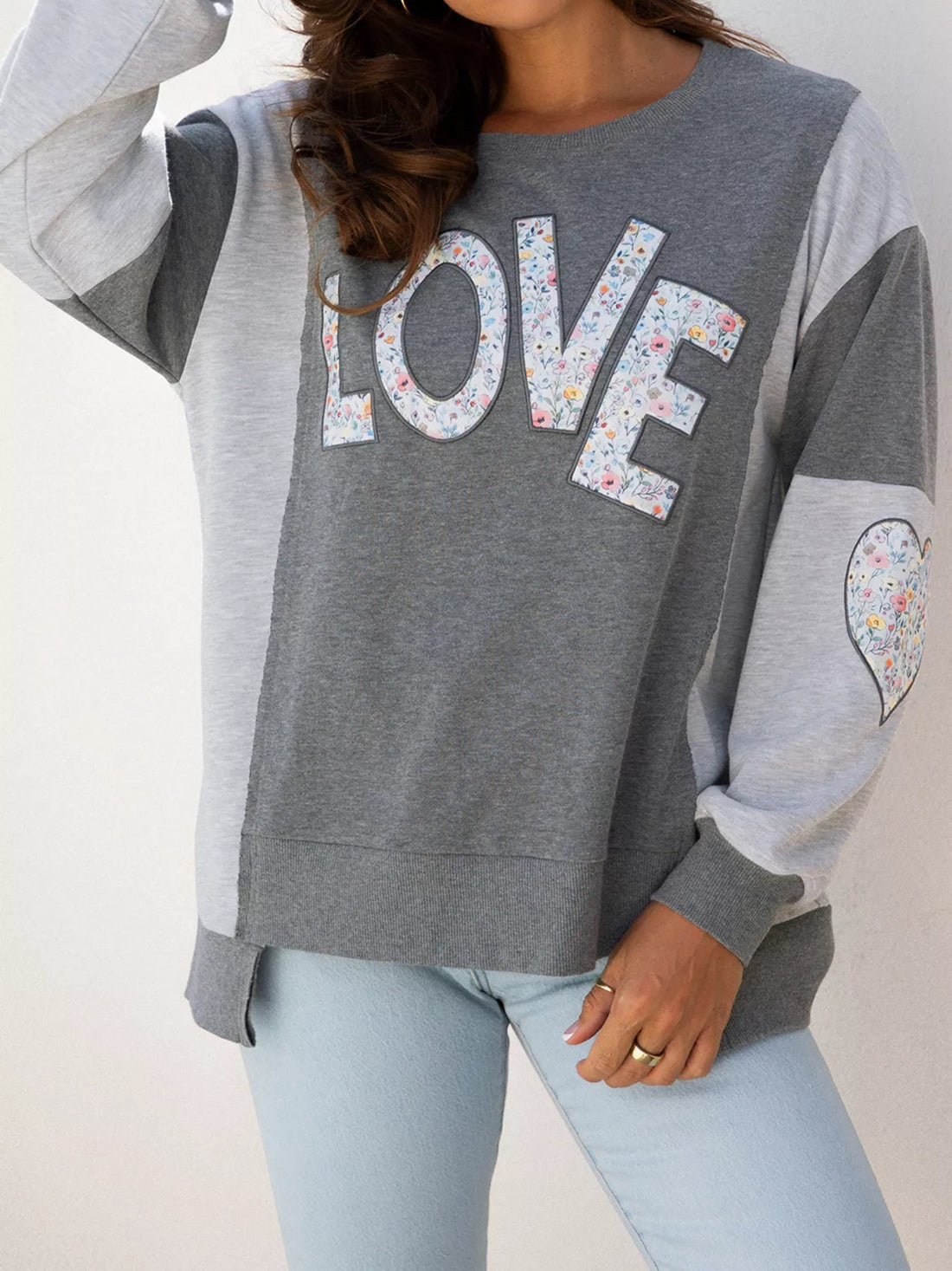 LOVE Graphic Exposed Seam Patchwork Uneven Hem Chic Sweatshirt designed for comfort and style at Lookzlike